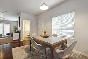 Dining area with dark wood-type flooring and brick wall