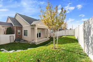 Rear view of house with a lawn, cooling unit, and a patio