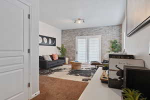 Carpeted living room with brick wall