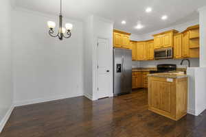 Kitchen with decorative light fixtures, stainless steel appliances, crown molding, and sink