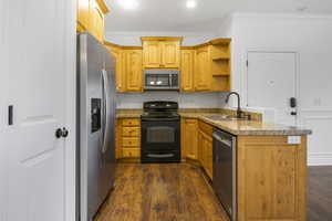 Kitchen with light stone countertops, sink, dark hardwood / wood-style flooring, crown molding, and appliances with stainless steel finishes