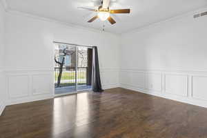 Empty room with dark wood-type flooring, ceiling fan, and crown molding