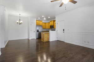 Kitchen featuring ceiling fan with notable chandelier, dark hardwood / wood-style floors, crown molding, and stainless steel appliances