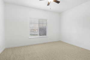 Carpeted spare room featuring ceiling fan