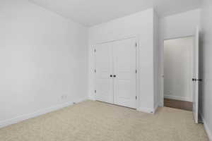 Unfurnished bedroom featuring light carpet and a closet