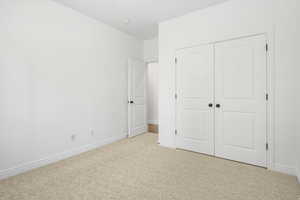 Unfurnished bedroom featuring light colored carpet and a closet