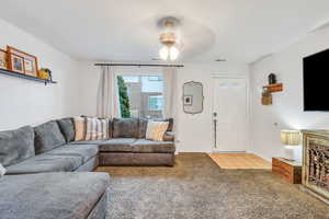 Living room with light carpet, a textured ceiling, and ceiling fan