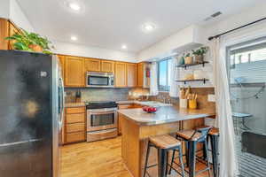 Kitchen with sink, a kitchen breakfast bar, backsplash, kitchen peninsula, and appliances with stainless steel finishes