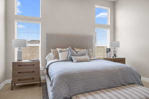 Carpeted bedroom with a towering ceiling and baseboards