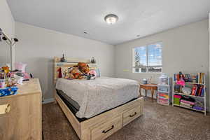 Bedroom featuring a textured ceiling and dark carpet