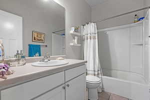 Full bathroom with tile patterned flooring, shower / bath combo with shower curtain, vanity, and toilet