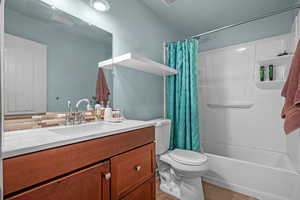 Full bathroom with toilet, shower / tub combo, vanity, and decorative backsplash