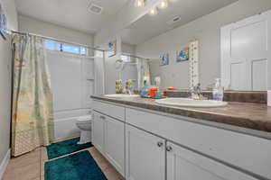 Full bathroom featuring toilet, vanity, tile patterned floors, and shower / bathtub combination with curtain