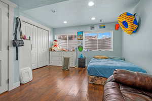 Bedroom with dark wood-type flooring, a textured ceiling, a closet, and radiator