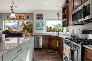 Kitchen featuring light stone countertops, sink, stainless steel appliances, and decorative light fixtures