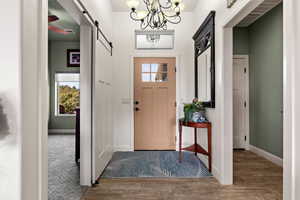 Entryway featuring carpet flooring, a barn door, and an inviting chandelier