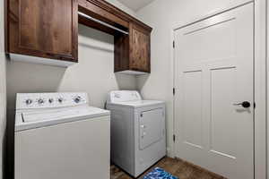 Clothes washing area featuring cabinets, independent washer and dryer, and dark hardwood / wood-style floors