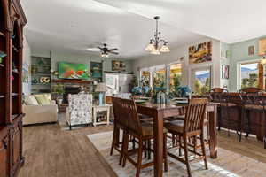 Dining space with built in shelves, a fireplace, ceiling fan with notable chandelier, and hardwood / wood-style flooring