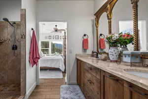 Bathroom with a tile shower, vanity, and ceiling fan