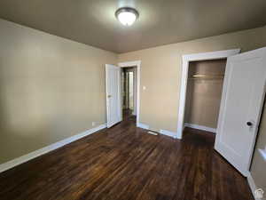 Unfurnished bedroom featuring dark hardwood / wood-style floors and a closet