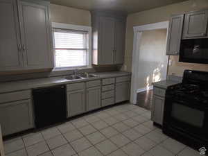 Kitchen with light tile patterned floors, sink, gray cabinetry, and black appliances