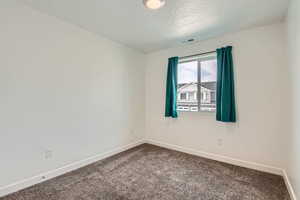 Carpeted spare room featuring a textured ceiling