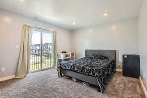 Bedroom featuring carpet flooring, black refrigerator, a textured ceiling, and access to outside