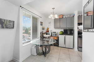 Kitchen featuring stainless steel range oven, a notable chandelier, and light tile patterned flooring