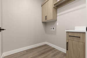 Laundry room with washer hookup, cabinets, and light wood-type flooring