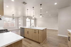 Kitchen with appliances with stainless steel finishes, a center island with sink, light hardwood / wood-style floors, and sink