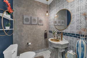 Bathroom featuring sink, tile patterned flooring, tile walls, and toilet