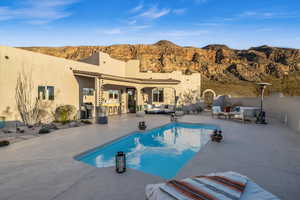 View of swimming pool with outdoor lounge area, a mountain view, and a patio