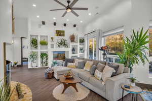 Living room featuring built in shelves, ceiling fan, dark wood-type flooring, and a high ceiling