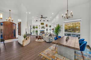 Living room with a towering ceiling, dark wood-type flooring, and ceiling fan with notable chandelier