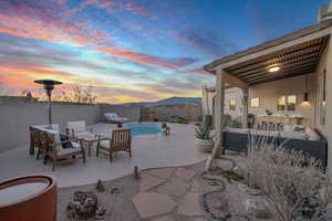 Patio terrace at dusk with an outdoor hangout area and a fenced in pool