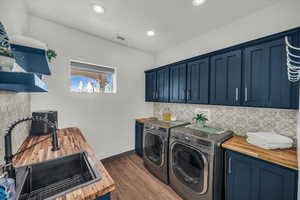 Laundry area with separate washer and dryer, dark wood-type flooring, cabinets, and sink