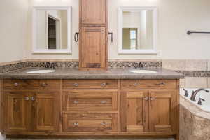 Bathroom with backsplash, tiled tub, and vanity