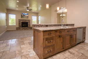 Kitchen featuring decorative light fixtures, a healthy amount of sunlight, ceiling fan with notable chandelier, and a fireplace