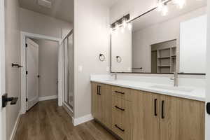 Bathroom with hardwood / wood-style flooring, vanity, and a shower with shower door