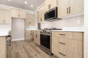 Kitchen with light brown cabinetry, stainless steel appliances, and light wood-type flooring