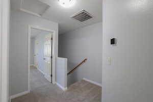 Hall featuring light carpet and a textured ceiling