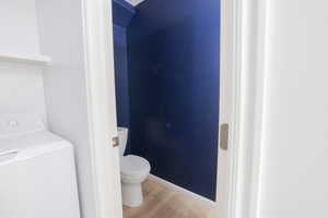 Bathroom with toilet, wood-type flooring, and washer / clothes dryer