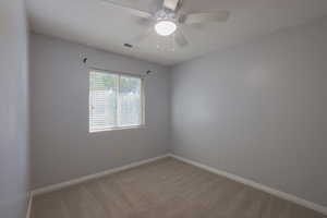 Carpeted empty room featuring ceiling fan