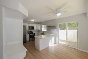 Kitchen featuring white cabinetry, sink, stainless steel appliances, kitchen peninsula, and light wood-type flooring