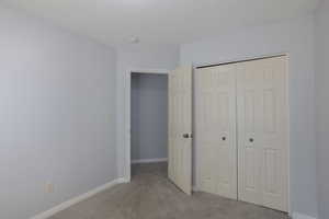 Unfurnished bedroom featuring light colored carpet and a closet