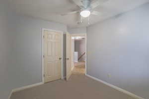 Empty room with ceiling fan and light colored carpet