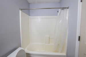 Bathroom with shower / bath combination with curtain and toilet