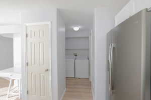 Hall with light wood-type flooring and washing machine and dryer