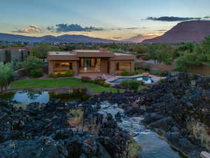 Back house at dusk featuring a mountain view, a yard, and a patio