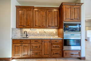 Kitchen featuring appliances with stainless steel finishes, tasteful backsplash, light stone counters, and sink